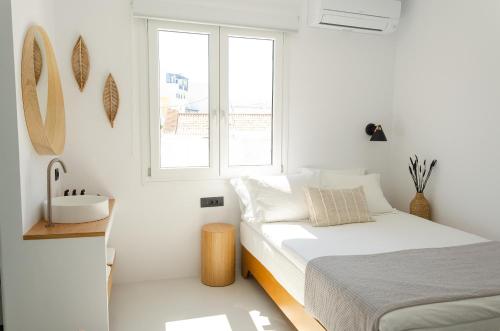 a white bedroom with a bed and a sink at Eleana Hotel in Tinos Town