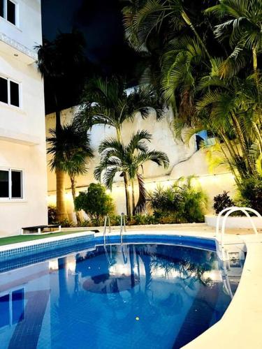 a swimming pool with palm trees next to a building at Casa Copan in Cancún