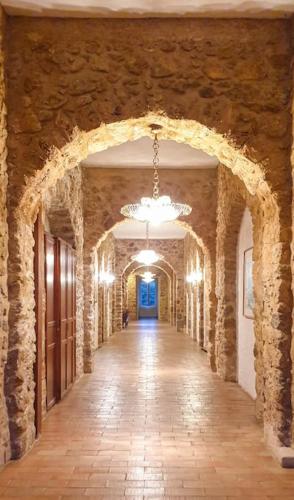 a hallway of a building with a stone wall and a chandelier at SPECIAL ! LE STUDIO DU CHATEAU in Tourrettes
