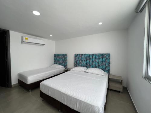 a bedroom with two beds and a window at Hotel Emerawaa Centro Historico in Ríohacha