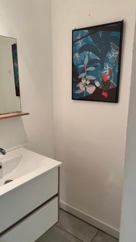 uma casa de banho com um lavatório e uma pintura na parede em 5- Le Nid em Poitiers