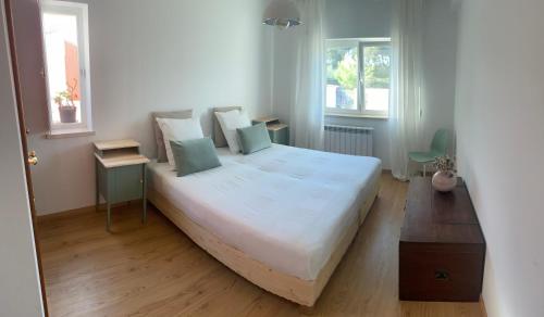 a bedroom with a large white bed and two windows at Casa da Várzea - O Castelo à Janela!!! in Óbidos