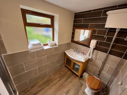 uma casa de banho com um lavatório e uma janela em Holly Farm Cottage em Flixton