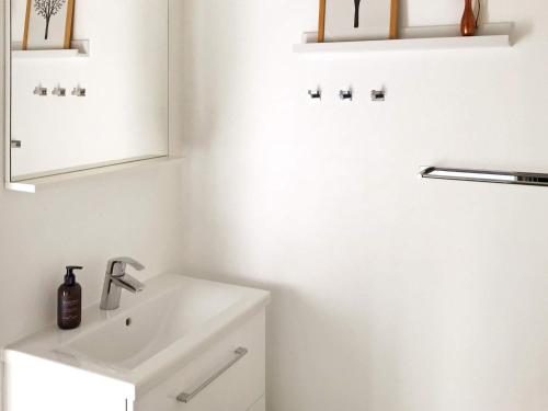 Baño blanco con lavabo y espejo en Two-Bedroom Holiday home in Aabenraa 2, en Aabenraa