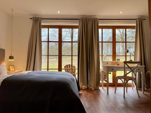 a bedroom with a bed and a desk and windows at Stimbekhof in Bispingen