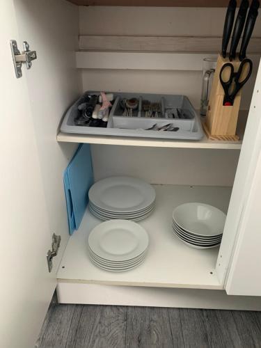 a stack of plates in a kitchen cabinet at Bulldog holidays 243 in Hemsby