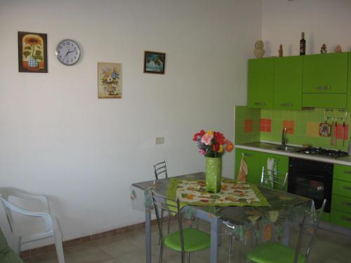 una cocina con una mesa con un jarrón de flores. en Appartamento al mare, Isola blu, en Marzamemi