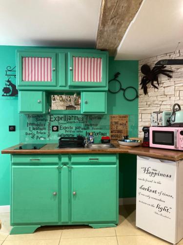 - une cuisine avec des placards verts et un mur vert dans l'établissement Les sorciers, la Diligence St Jean de Losne, à Saint-Jean-de-Losne