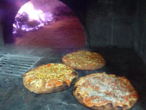 three pizzas are cooking in a pizza oven at Hotel Il Cortile in Custonaci