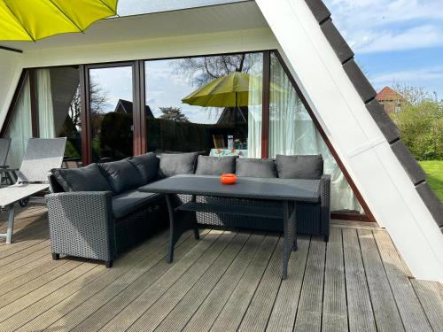 eine Terrasse mit einem Sofa und einem Tisch auf einer Terrasse in der Unterkunft Haus Blume in Carolinensiel