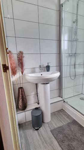 a white bathroom with a sink and a shower at RTM COMFORTABLE Home in Basildon