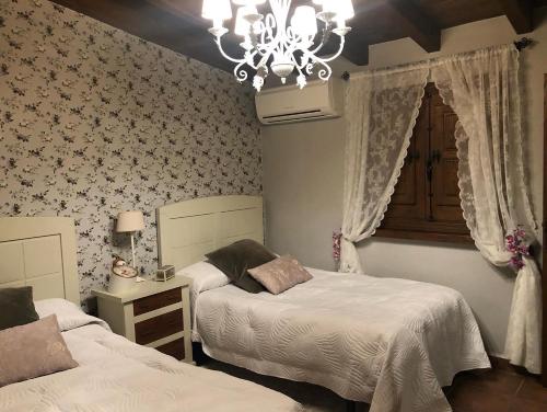 a bedroom with two beds and a chandelier at Finca Vergel in Gata