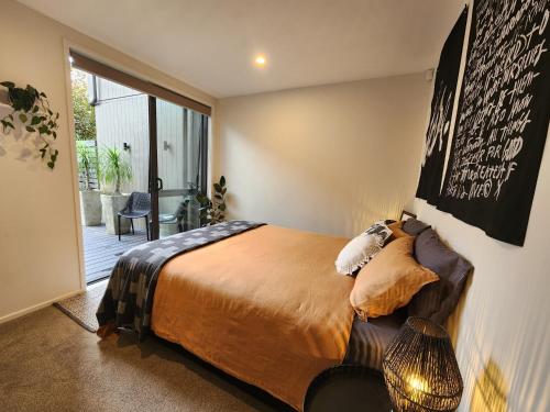 1 dormitorio con cama y ventana grande en Cosy Luxury City Fringe en Auckland