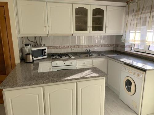a kitchen with white cabinets and a stove top oven at Casa 28 in Pataias