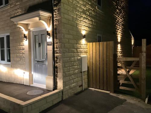 a door to a house at night with lights at Cheshire View in Buxton