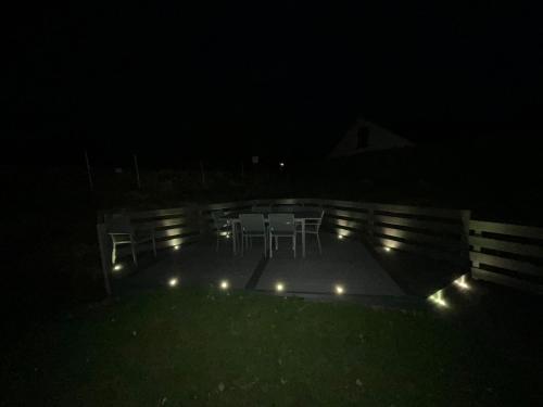 a patio with chairs and lights at night at Cheshire View in Buxton