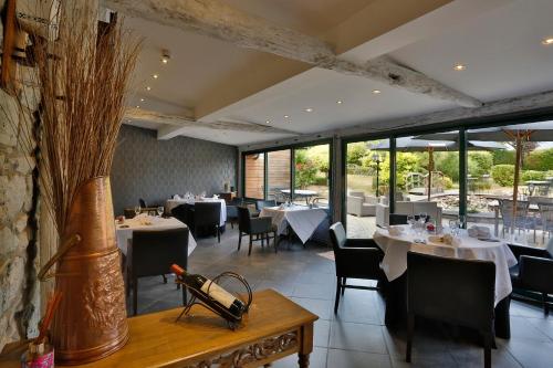 un comedor con mesas, sillas y ventanas en Auberge Des Cretes, en Falmignoul