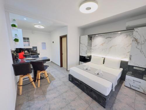 a bedroom with a white bed and a desk and chairs at Nikos Apartments Corfu in Agios Stefanos
