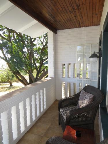 a porch with a rocking chair and a tree at White House Lodge in White River
