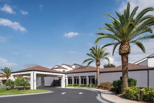 a building with palm trees in front of it at Courtyard by Marriott Orlando Airport in Orlando