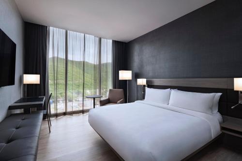 a bedroom with a large white bed and a large window at AC Hotel by Marriott Monterrey Valle in Monterrey