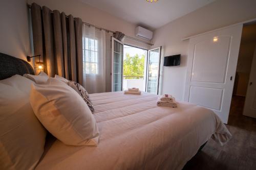 een slaapkamer met een groot wit bed en een raam bij Andromeda apartments in Spáta