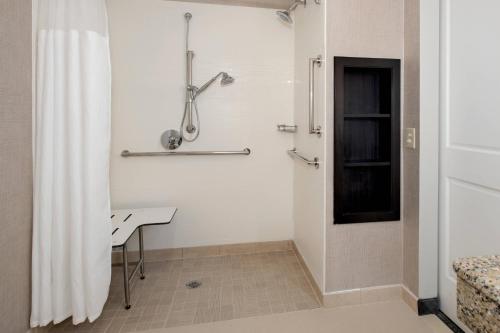 a white bathroom with a shower and a table at Residence Inn Syracuse Carrier Circle in East Syracuse