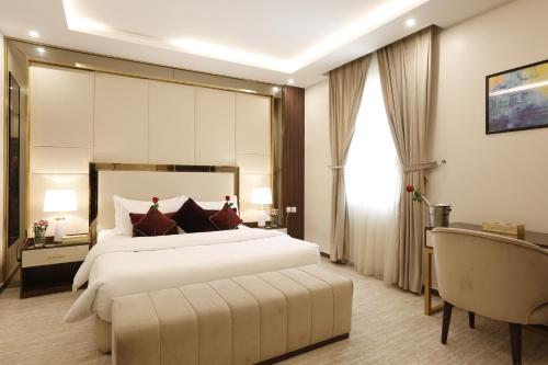 una camera con un grande letto bianco e una sedia di فندق وايت مون للأجنحة الفندقية a Khamis Mushayt
