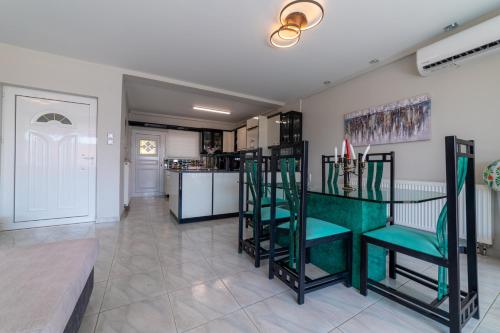 a living room with green chairs and a kitchen at Seaside Serenity in Volos