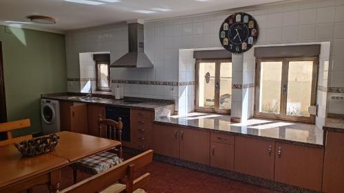 a kitchen with a table and a clock on the wall at Casa Millar. in Huergas y El Millar