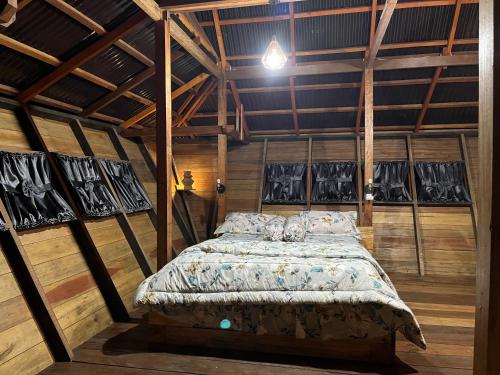 a bedroom with a bed in a room with wooden walls at Para para cafe & cottage in Berastagi