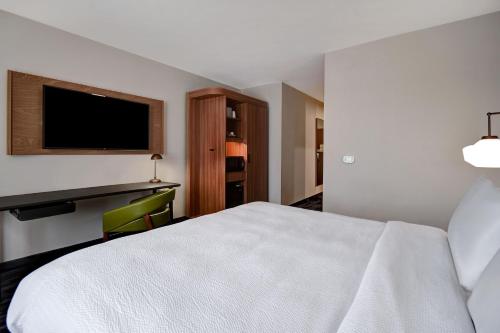 a hotel room with a white bed and a desk at Fairfield by Marriott Inn & Suites Grand Rapids Wyoming in Wyoming