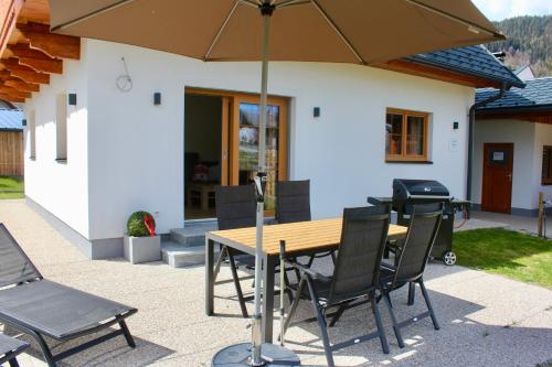 a wooden table and chairs with an umbrella on a patio at Chalet Mama in Pruggern