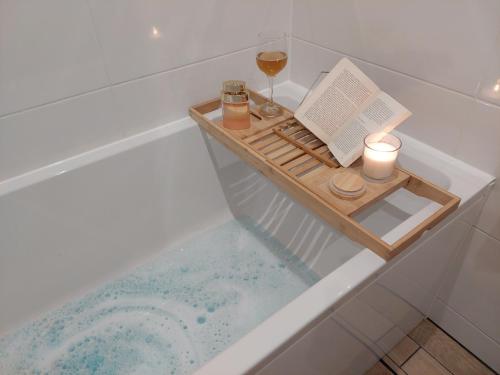 een bad met een boek en kaarsen en een glas wijn bij Apartament Finezja in Sandomierz