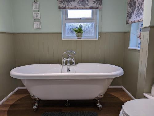 a white bath tub in a bathroom with a window at The Cottage in Tetbury