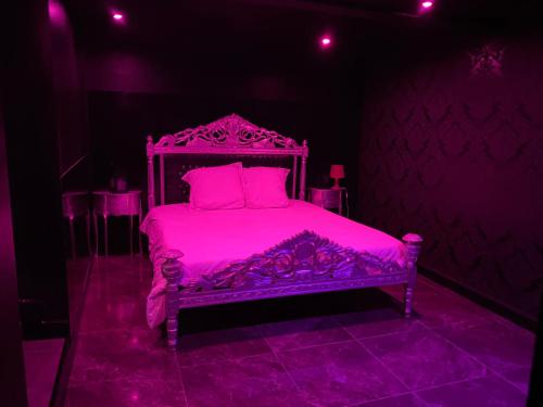 La Suite Marylin, Loft de 90m2 avec Sauna et Jacuzzi في ريوم: غرفة نوم مع سرير وردي في غرفة مظلمة