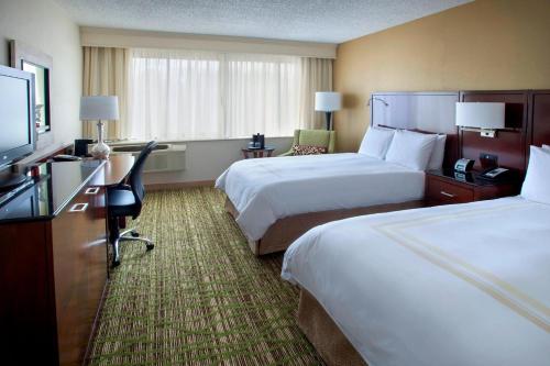 a hotel room with two beds and a flat screen tv at Boston Marriott Peabody in Peabody