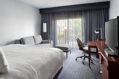 a hotel room with a bed and a desk and a television at Courtyard by Marriott West Palm Beach in West Palm Beach