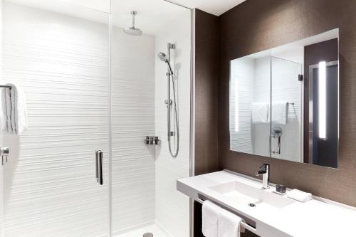 a bathroom with a shower and a sink and a mirror at AC Hotel By Marriott Salt Lake City Downtown in Salt Lake City