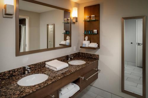 Baño con 2 lavabos y espejo en Delta Hotels by Marriott Huntington Mall en Barboursville