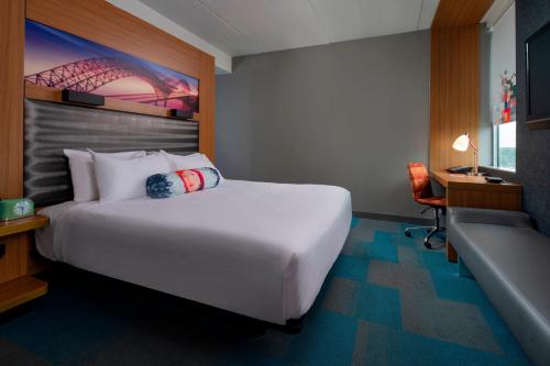 um quarto de hotel com uma grande cama branca e uma secretária em Aloft Hotel Rogers Bentonville em Rogers