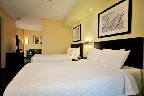 a hotel room with two beds with white sheets at SpringHill Suites Galveston Island in Galveston