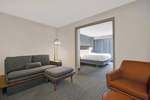 a hotel room with a couch and a bed and a mirror at Courtyard Chicago Elmhurst/Oakbrook Area in Elmhurst