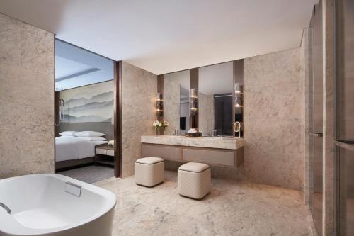 a bathroom with a tub and a bedroom with a bed at Wenzhou Marriott Hotel in Wenzhou