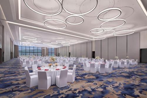 un salón de banquetes con mesas y sillas blancas y una lámpara de araña en Wenzhou Marriott Hotel, en Wenzhou