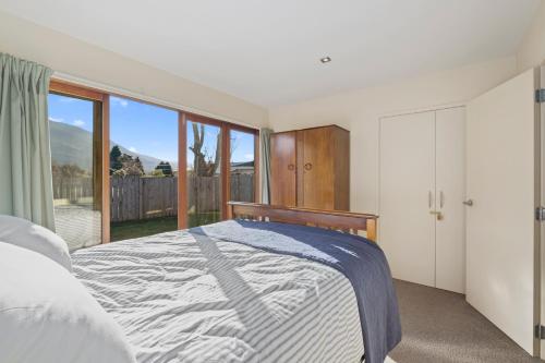 a bedroom with a bed and a large window at Lake Hawea Haven - Lake Hawea Holiday Home in Lake Hawea
