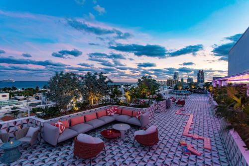 a rooftop patio with a couch and tables and chairs at Moxy Miami South Beach in Miami Beach
