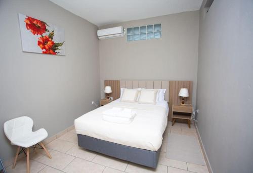 ein Schlafzimmer mit einem weißen Bett und einem weißen Stuhl in der Unterkunft Chonguile Villa 1 Modern Minimalist in Matola in Matola
