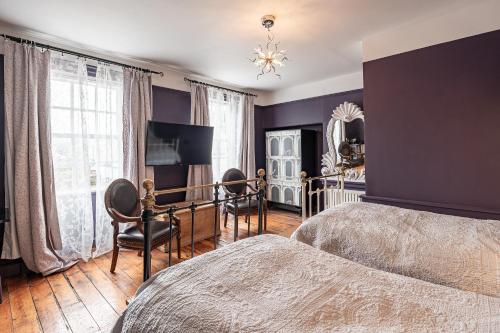 SkinningroveにあるMoonfleet Guest Houseの紫の壁のベッドルーム(ベッド、椅子付)
