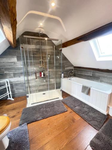 a bathroom with a shower and a toilet and a tub at Luxury Country Cottage With A View in Enstone